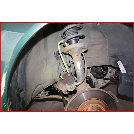 Nahaufnahme der Radaufhängung eines Autos mit Federung, Bremsscheibe und gelber Leitung.